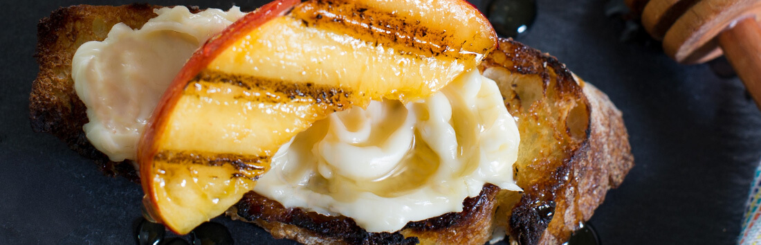 The Laughing Cow cheese spread over a slice of toast with grilled peach