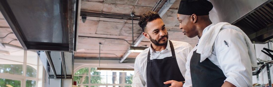 Two chefs speaking in a kitchen