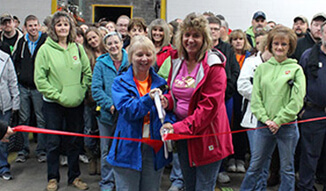 Two women cutting a red ribbon with ceremonial scissors