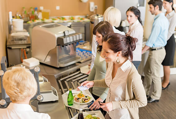 A woman paying for a tray of food in a checkout line