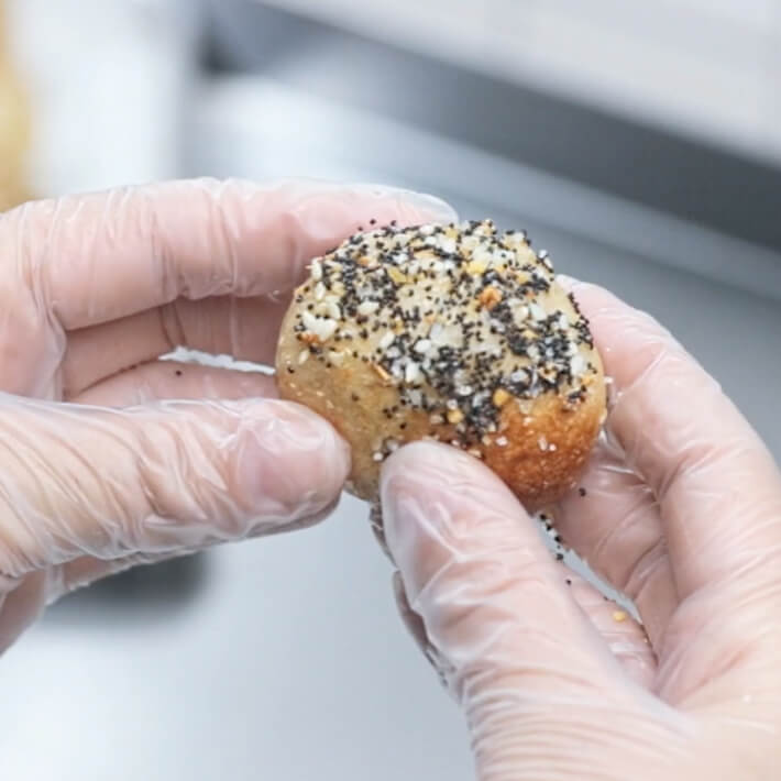 Two gloved hands holding a Boursin fried cheese curd